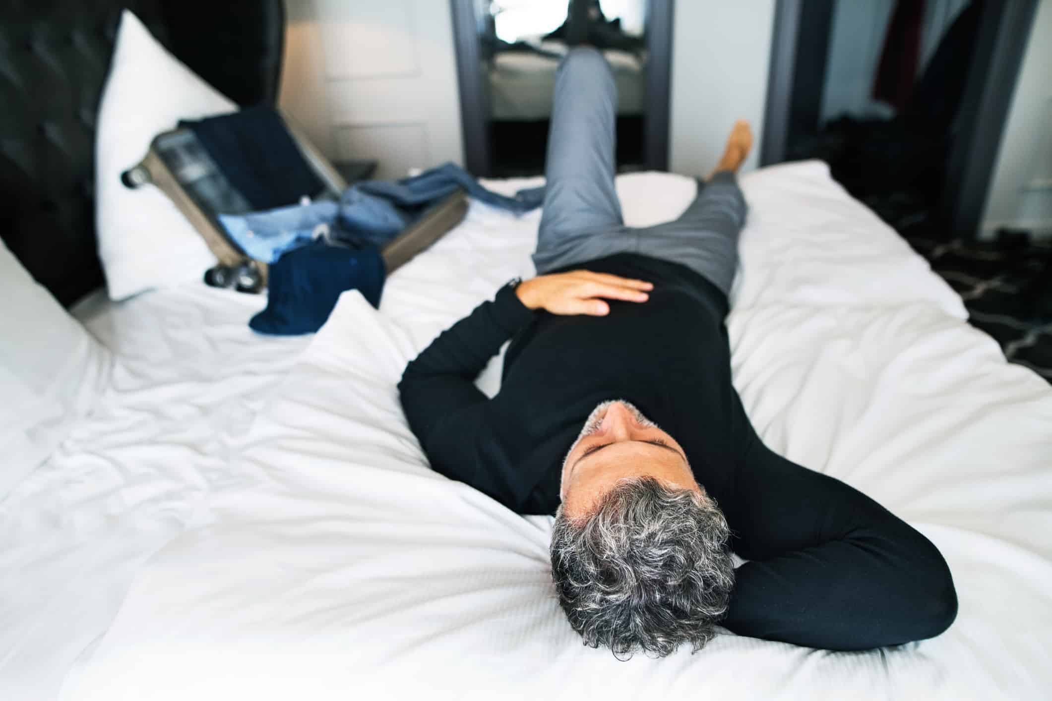 Mature businessman in a hotel room. man lying on a bed, resting. Image credit: Halfpoint