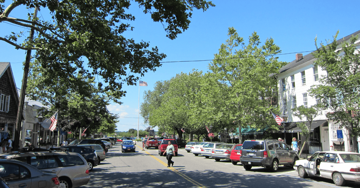 a street lined with parked cars and trees.