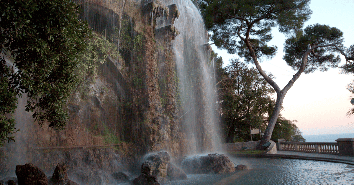 a large waterfall with a man standing next to it.
