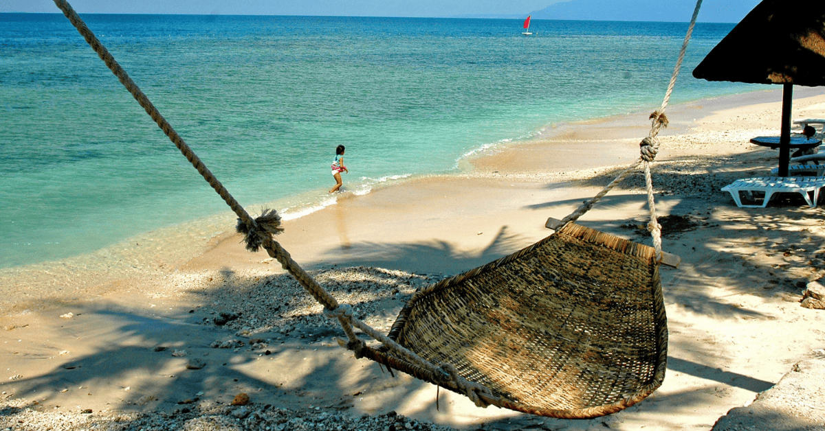 a hammock hanging from a rope on the beach.