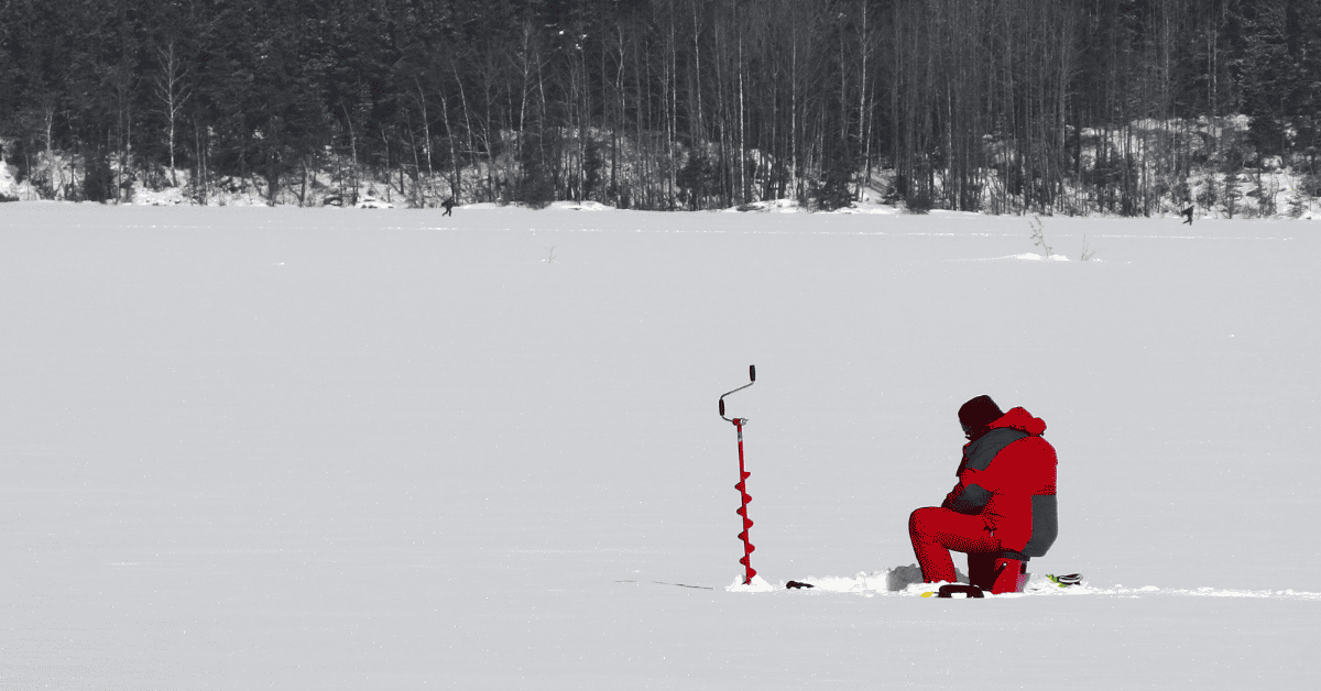 a man sitting in the snow next to a pole.
