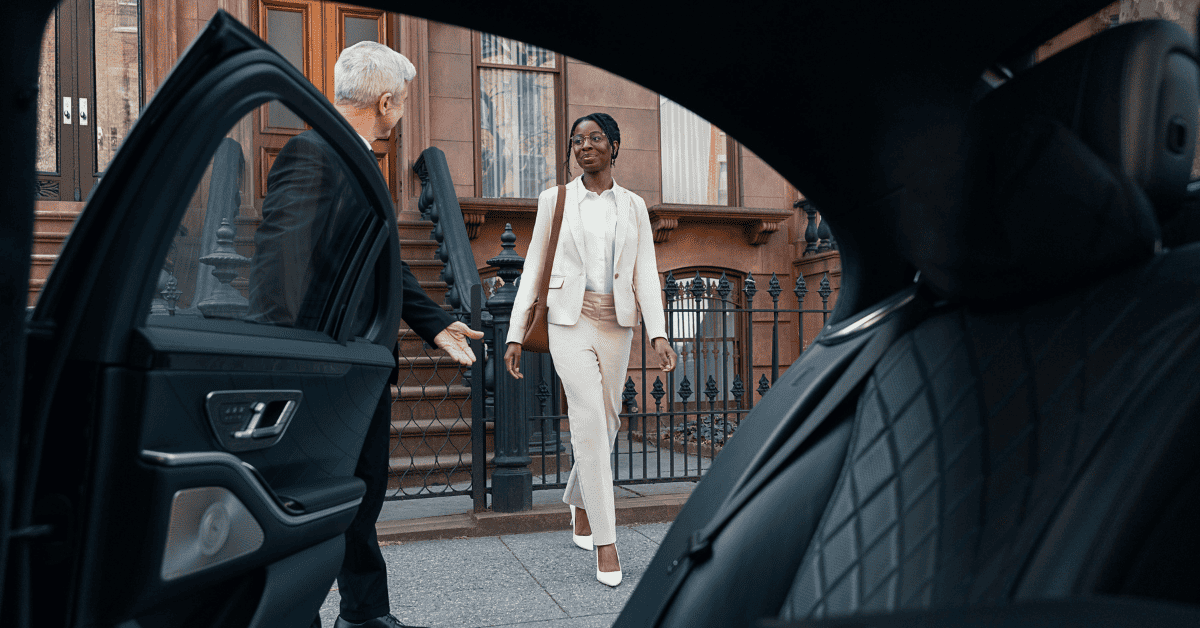 a woman in a white suit walking toward a car.