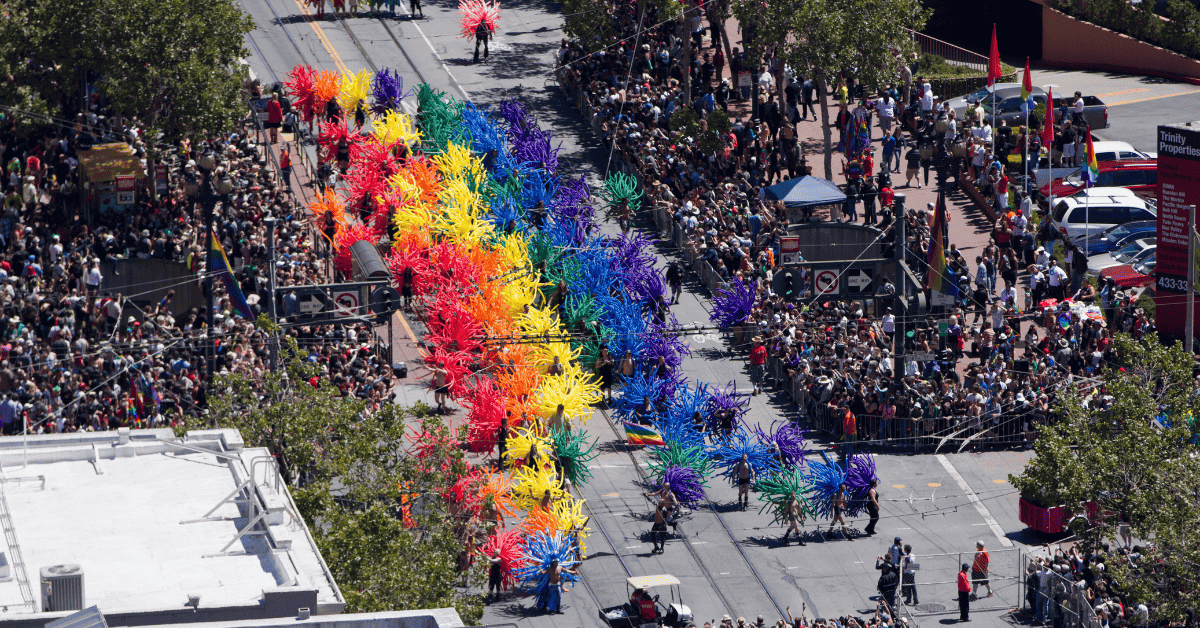 a parade with a rainbow colored float in the middle of the street.