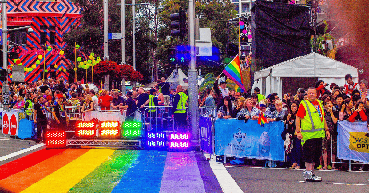 A group of people in a street with a rainbow flag.