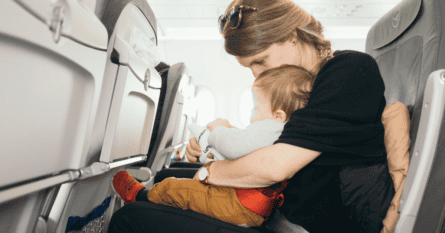 a woman is holding a baby in an airplane seat.
