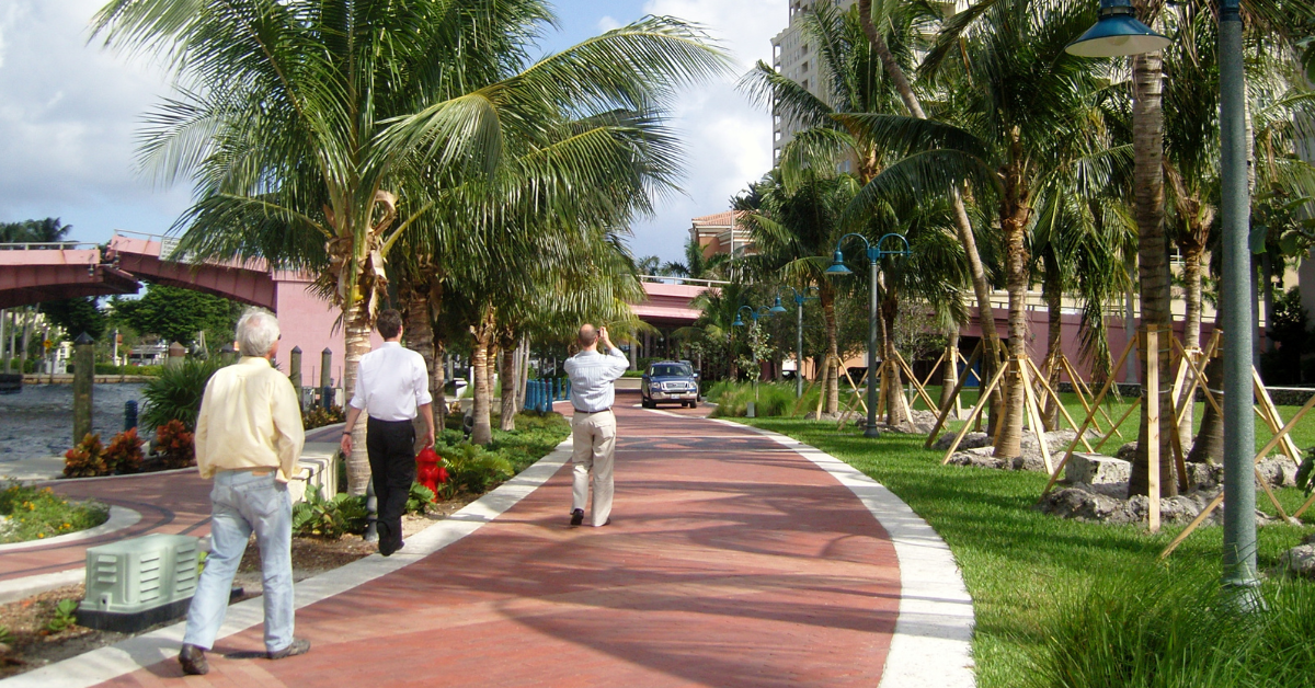 people walking on a sidewalk with palm trees