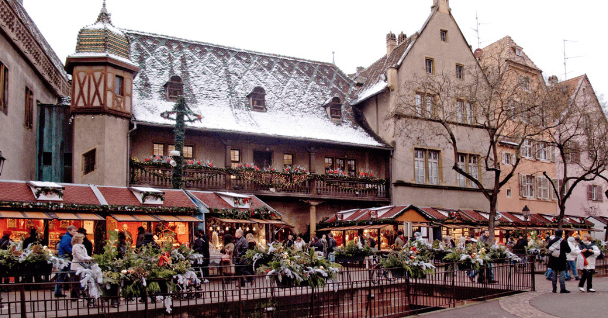 A bustling flower market in a snowy European town square with people browsing