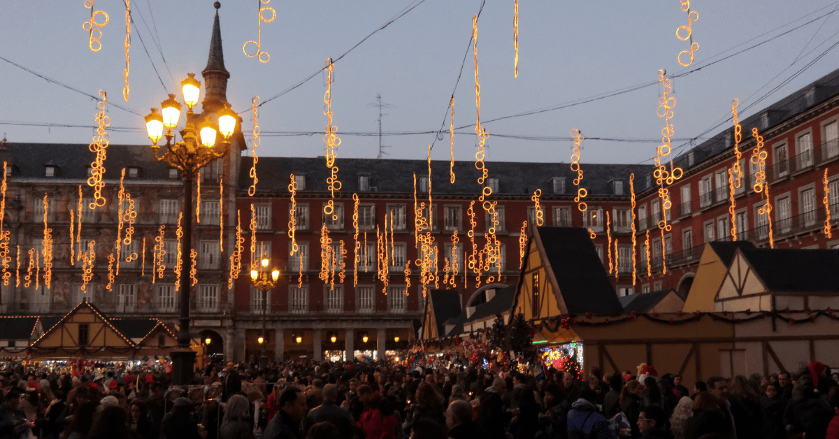 a crowd of people in a city under ornaments and lights