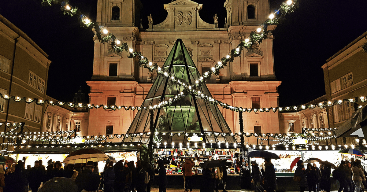 a building with a pyramid shaped structure with lights and people walking around