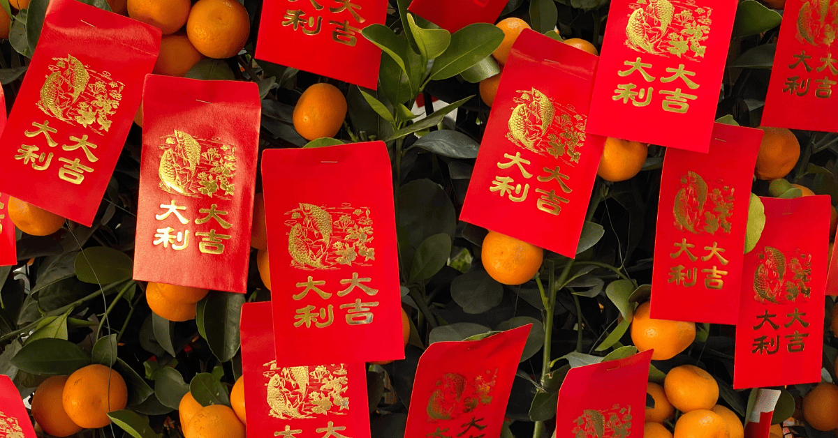 a group of oranges with red packets on a tree