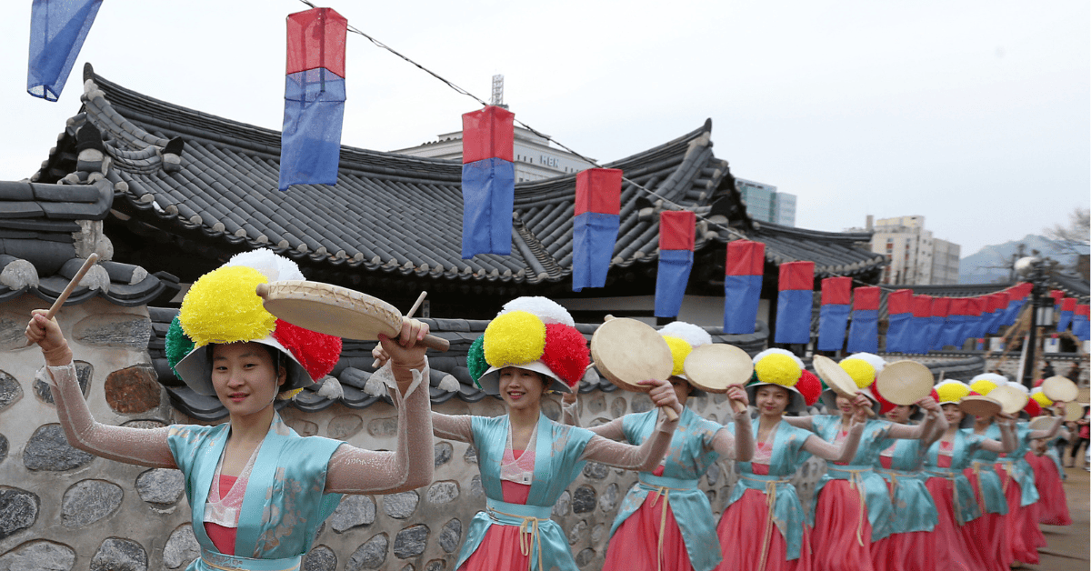 a group of Asian women in colorful clothing holding drums
