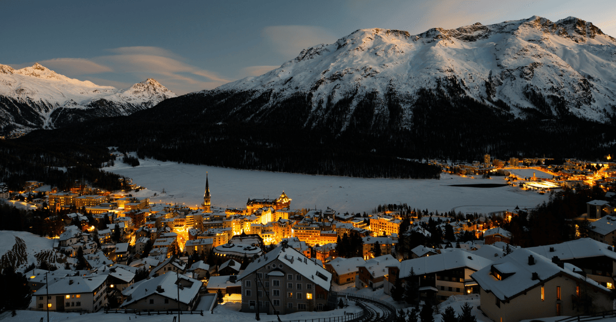 a mountain town lit up in the snow