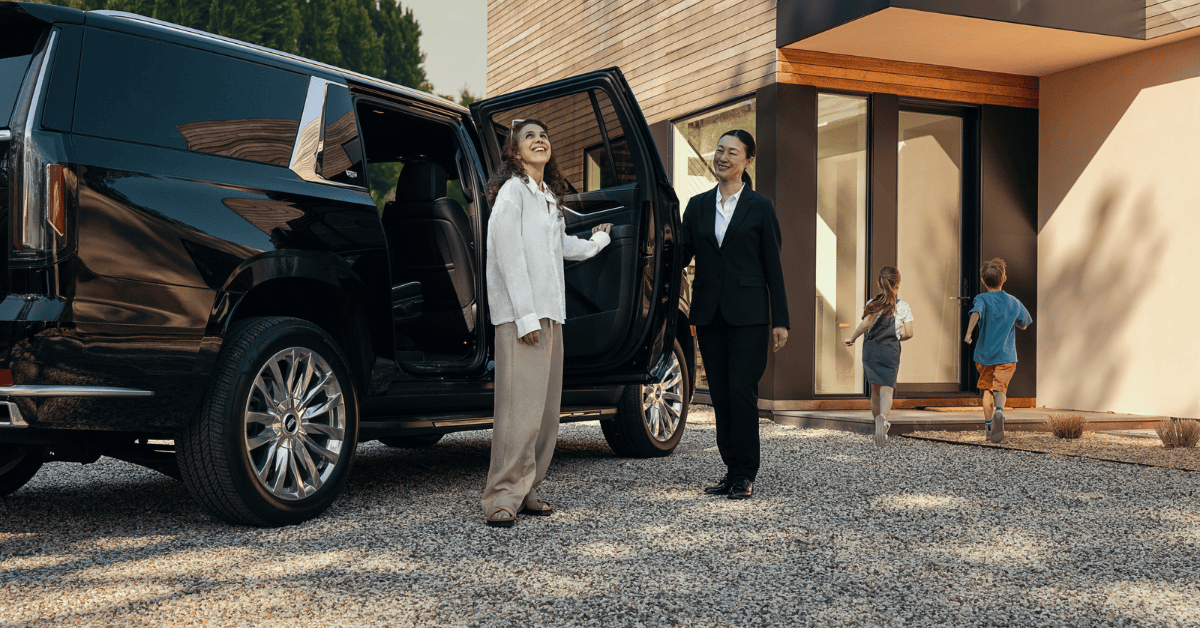 A female chauffeur and a woman standing next to black SUV