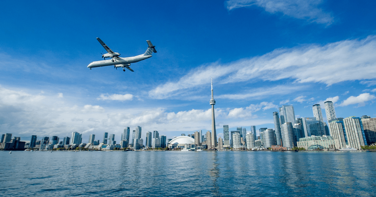 A large airplane soaring above a city with a body of water, showcasing the beauty of urban and natural landscapes.